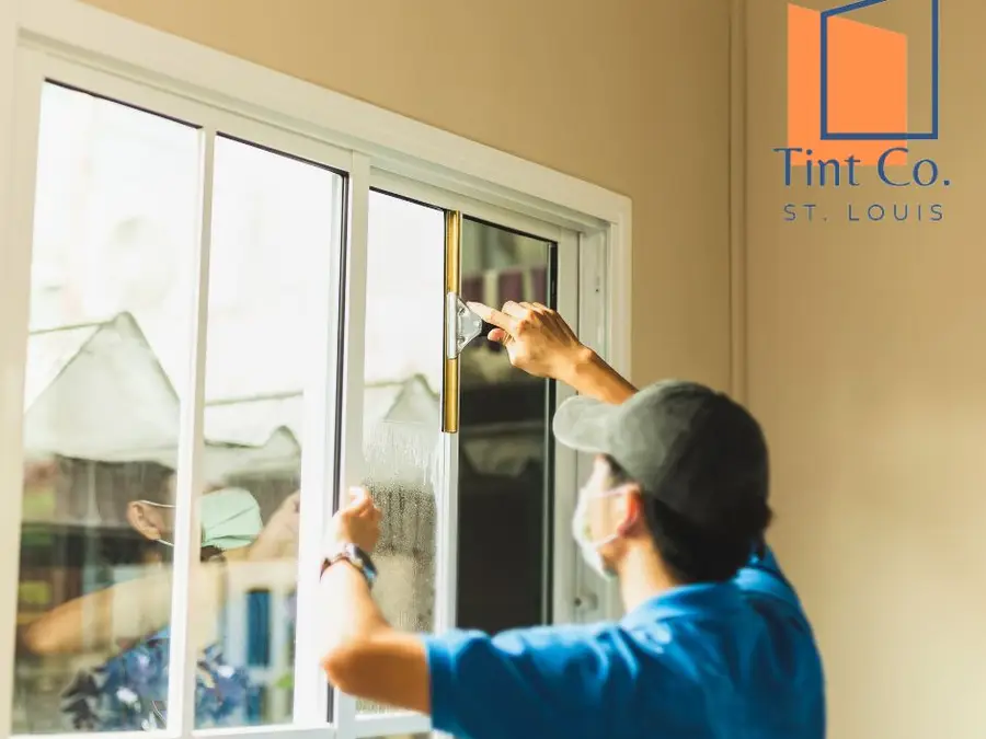 Window film installer applying tint to a home window in St. Louis